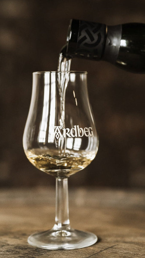 Whisky being poured into a Ardbeg glass with a blurred background