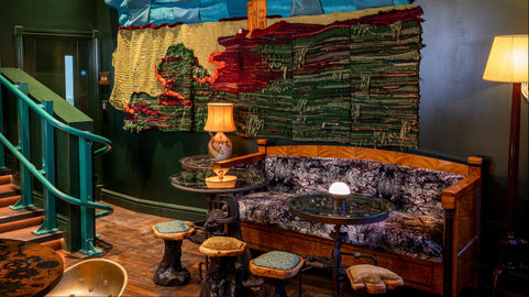 Interior of a cozy restaurant with colorful wall art and wooden furniture. By Islay Quilters.